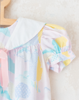 Pastel colored overalls with tree print and doll on a string | 18-24 months