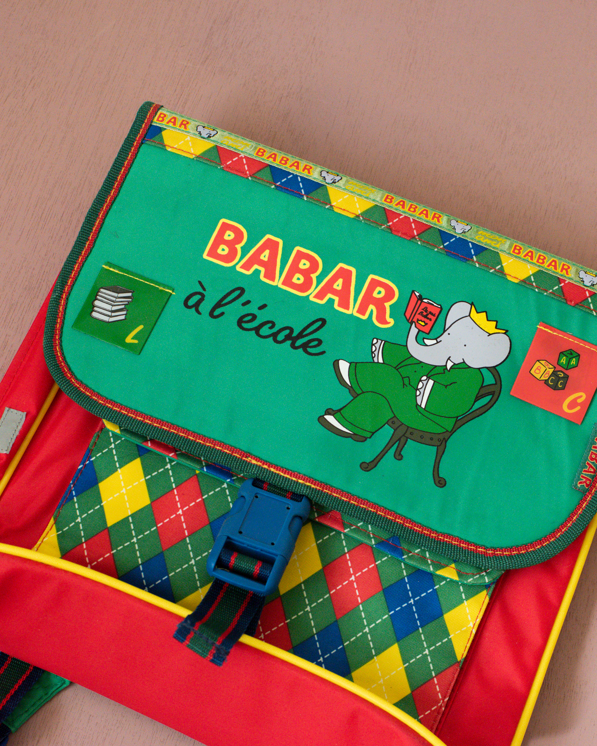 ילקוט ירוק עם מעוינים צבעוניים והמלך בבר