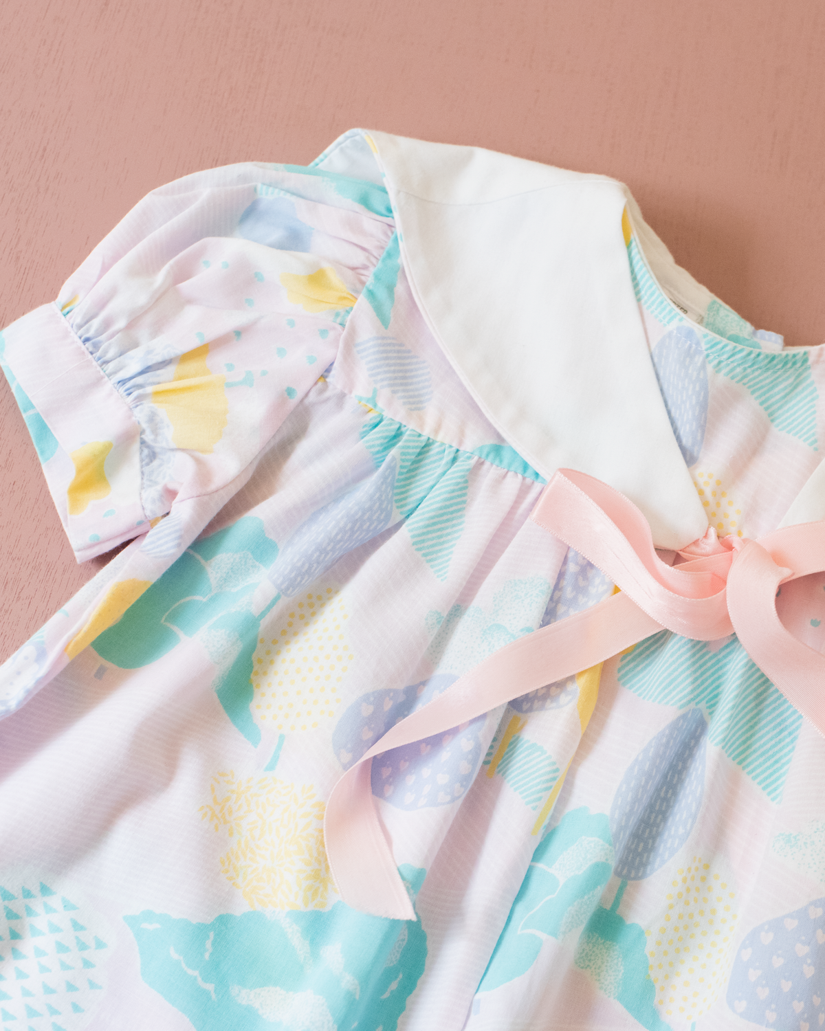 Pastel colored overalls with tree print and doll on a string | 18-24 months