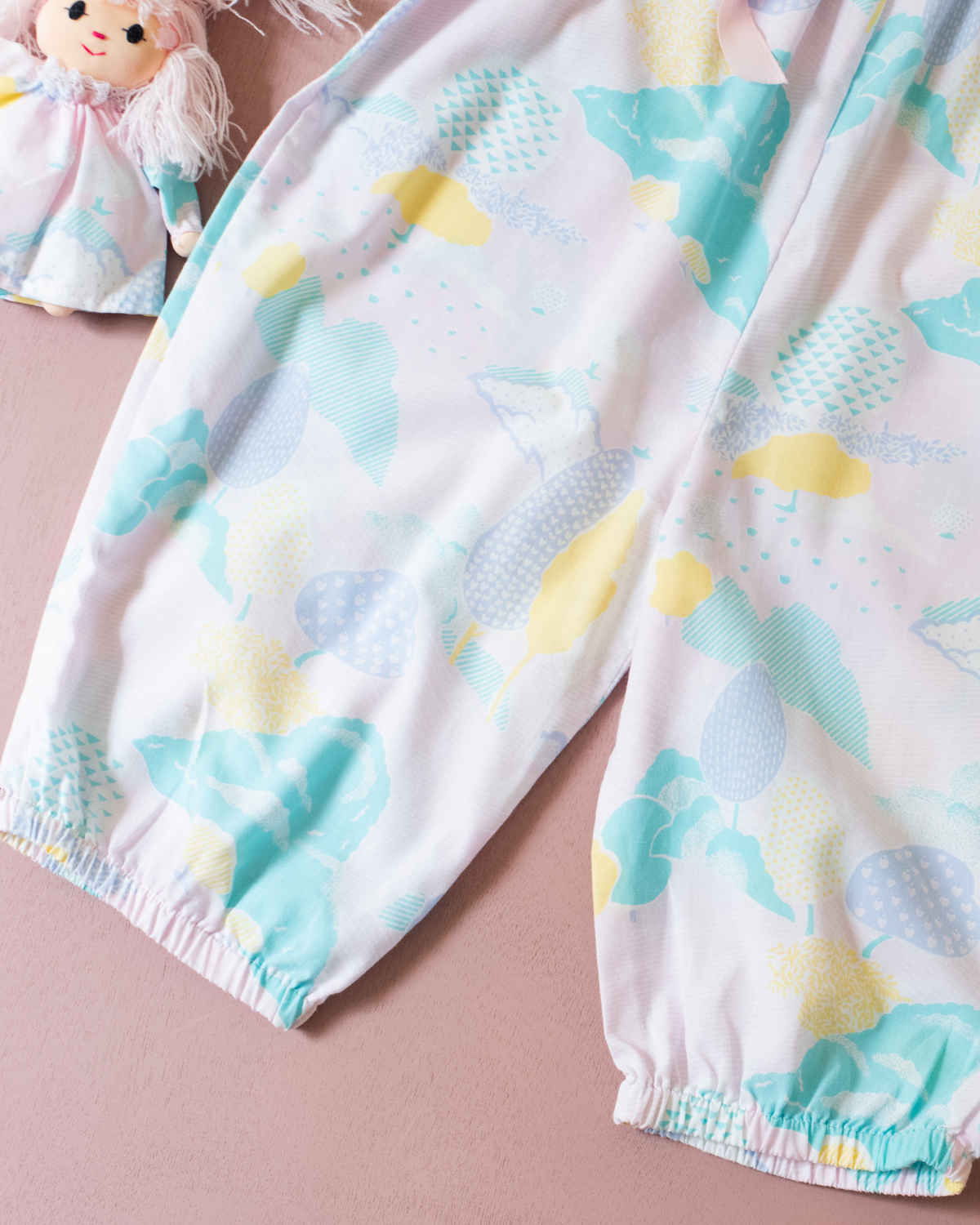 Pastel colored overalls with tree print and doll on a string | 18-24 months