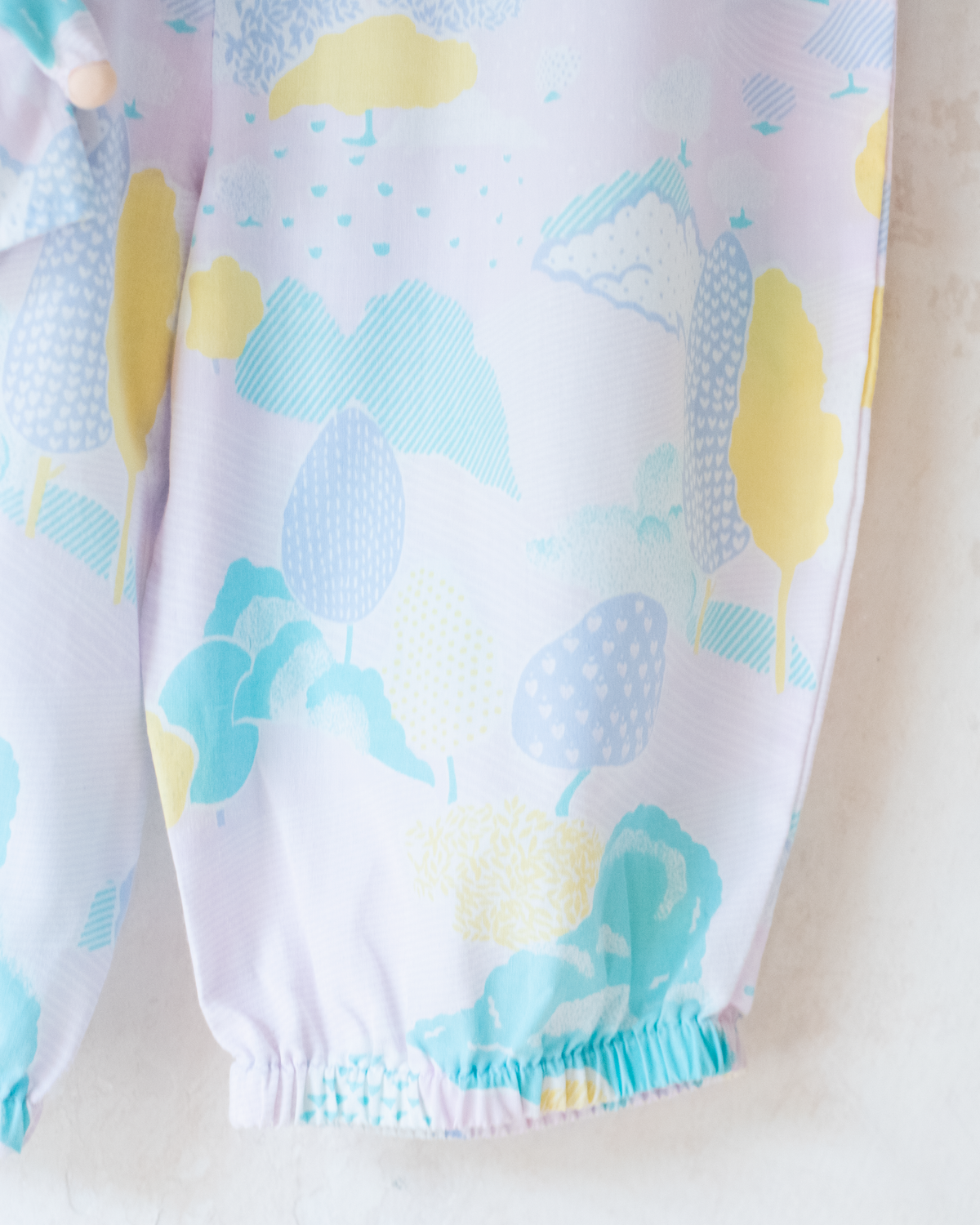 Pastel colored overalls with tree print and doll on a string | 18-24 months