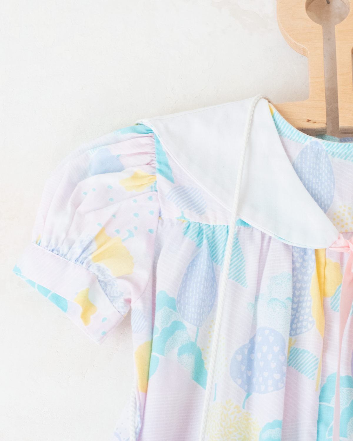Pastel colored overalls with tree print and doll on a string | 18-24 months
